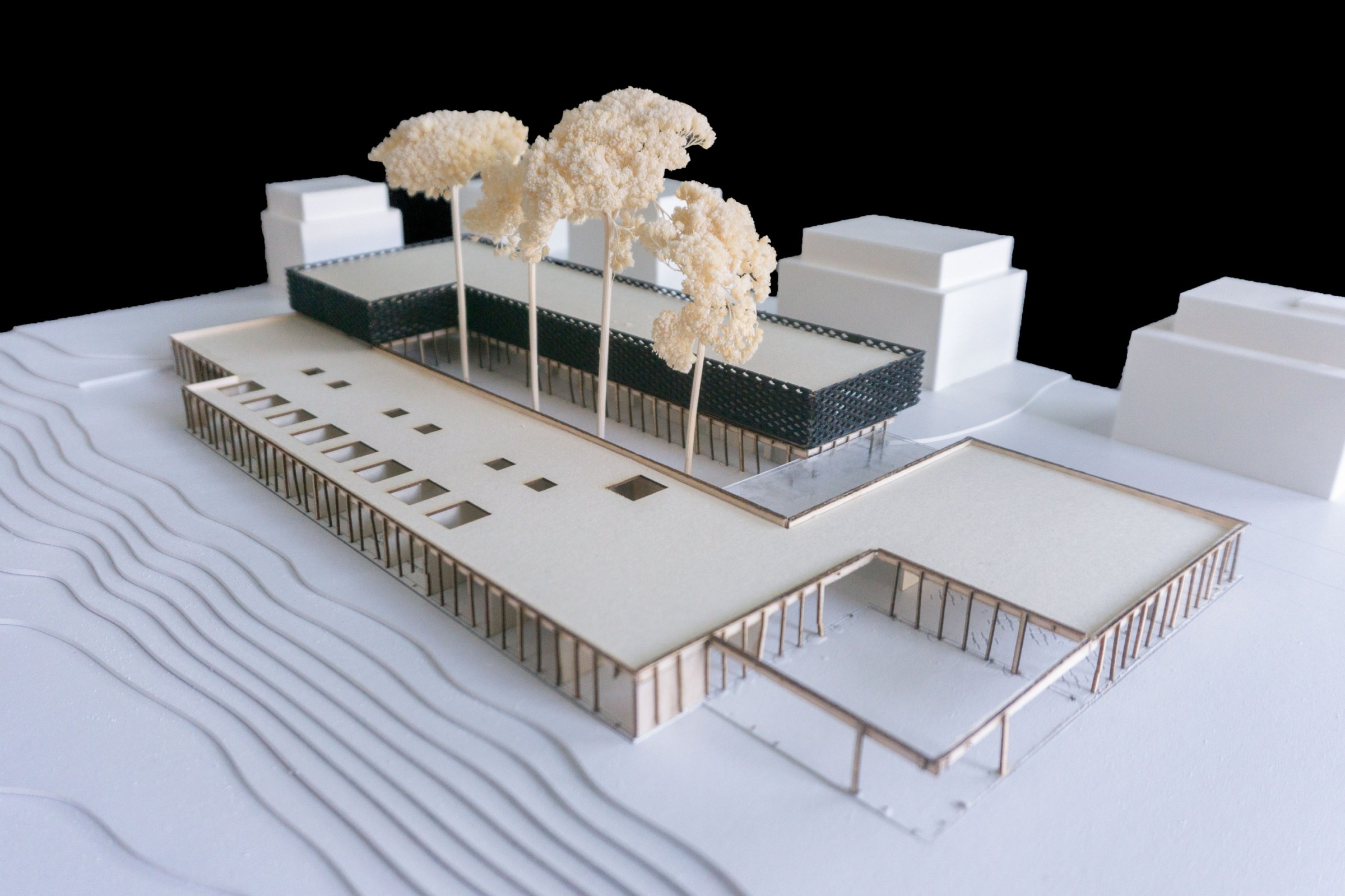 Close physical model view of the hospice courtyard, roofscape, trees and surrounding model buildings.