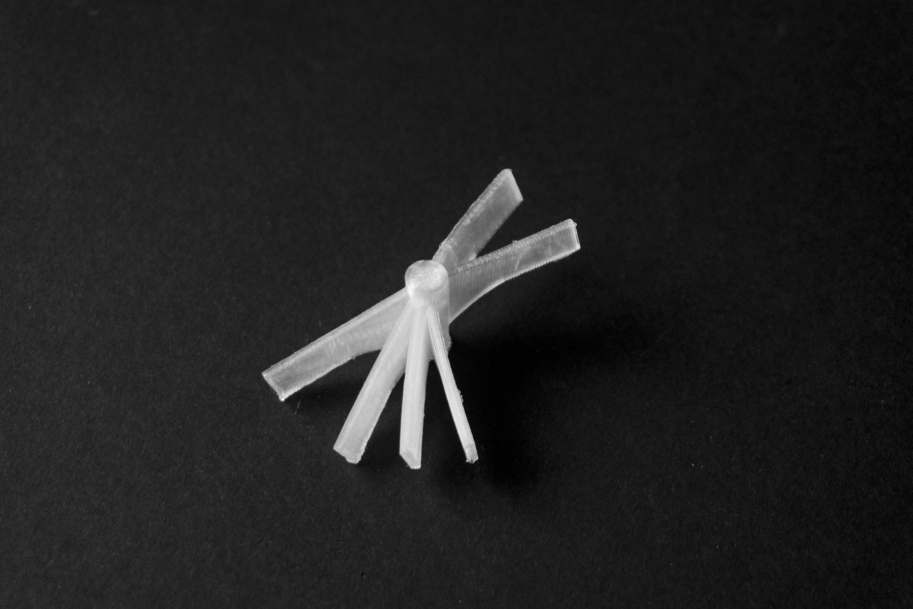 Photograph of a translucent 3D printed structural node prototype on a dark background.